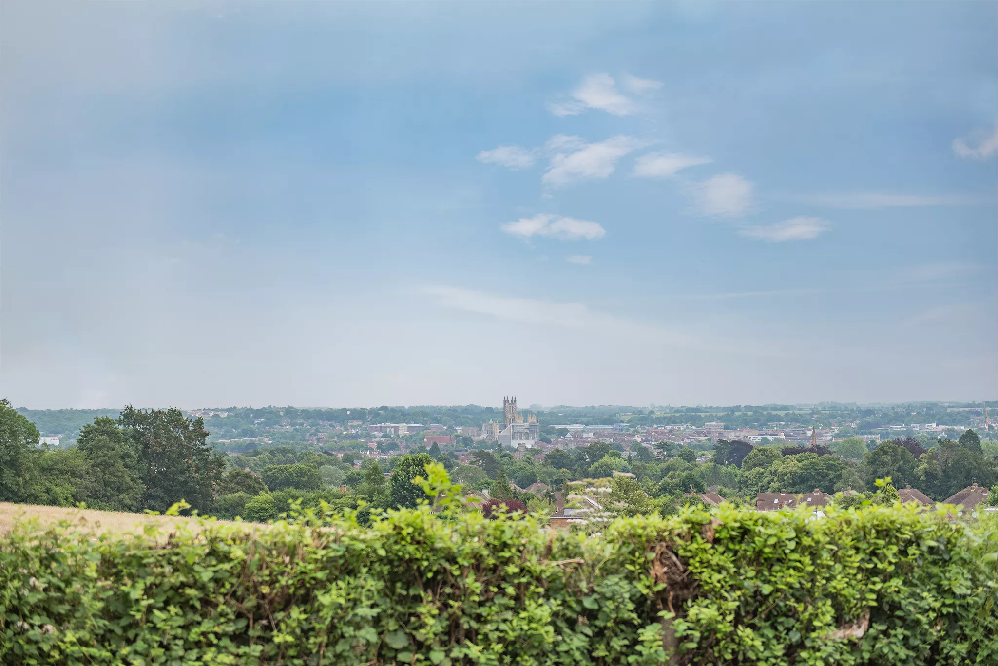 A wide shot overlooking Canterbury City Centre in Kent, with blue skies and lots of greenery.