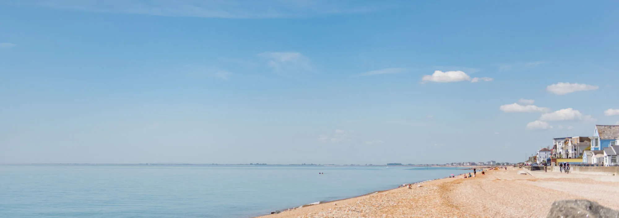 A very sunny photo of the sea and pebbled beach at Sandgate, Kent.