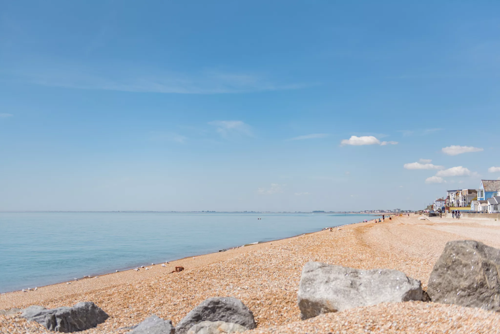 A very sunny photo of the sea and pebbled beach at Sandgate, Kent.