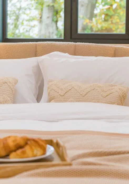 a plate of croissants sits atop a neutrally made bed at The Grain Store