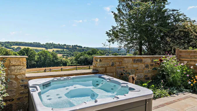A beautiful hot tub looking out to the countryside and blue skies at Dairy Barn, a holiday home in Blackham village just outside of Tunbridge Wells.