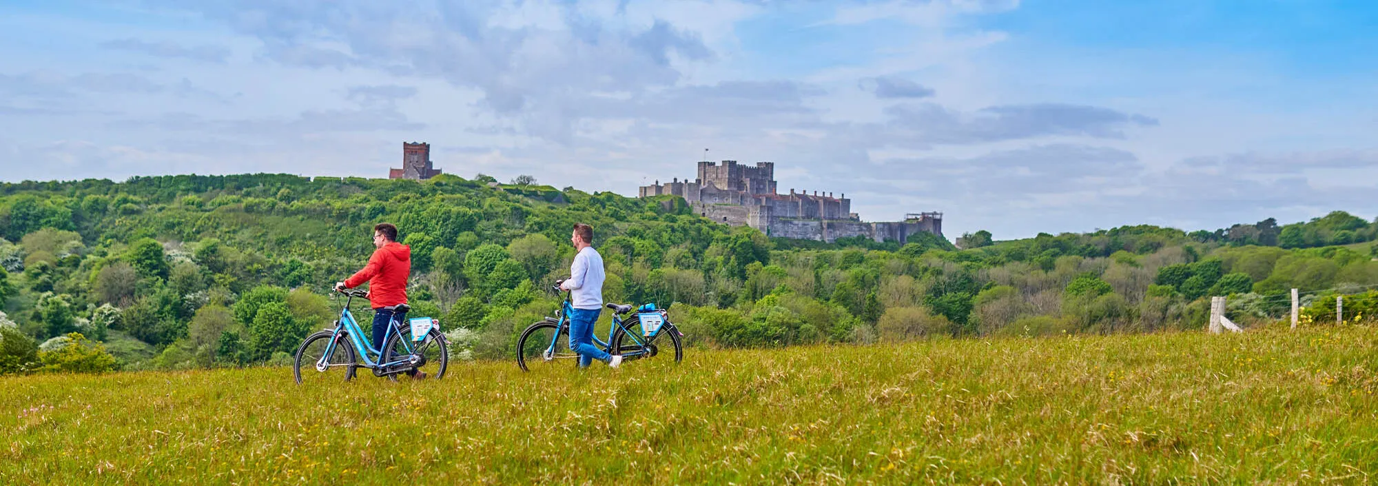 Two men with hired electric bikes in a field along the Kent coastline