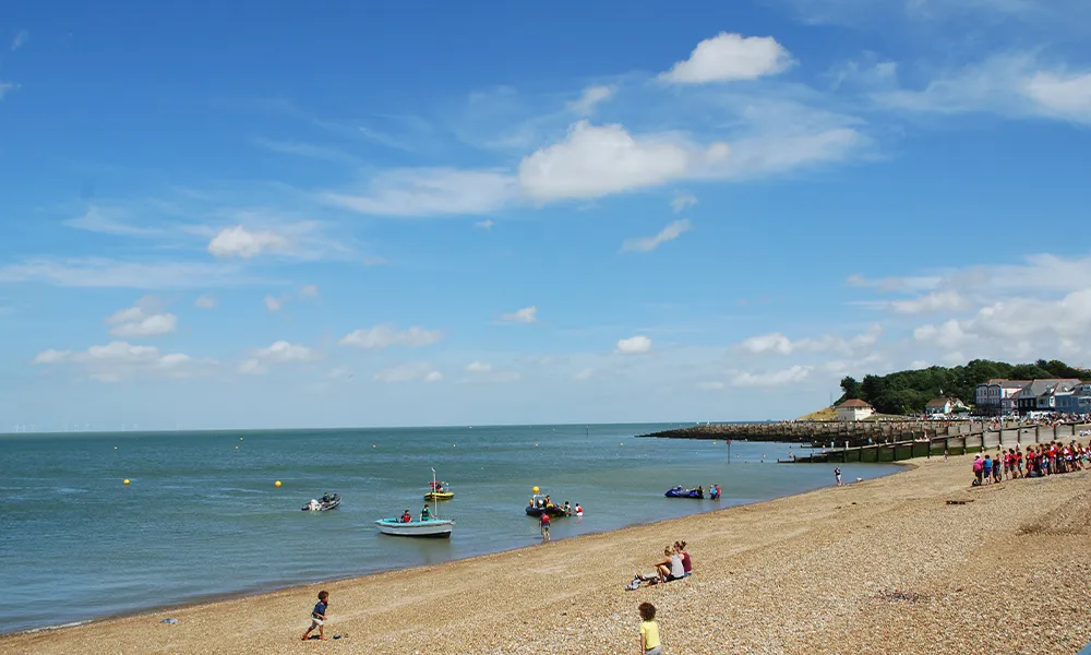 Whitstable sea front in Kent, there's people enjoying water sports and soaking up the sunshine.
