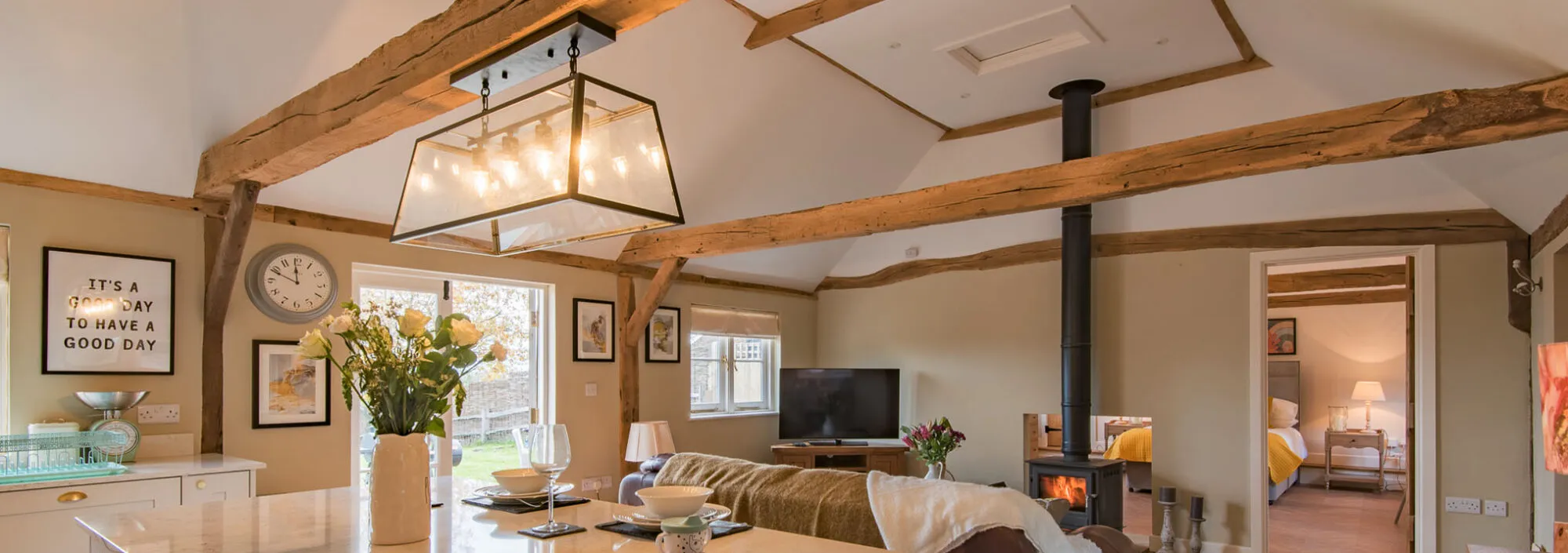 The inside of Cart Lodge, a cosy holiday home, with a log burner, large sofa and open plan kitchen.