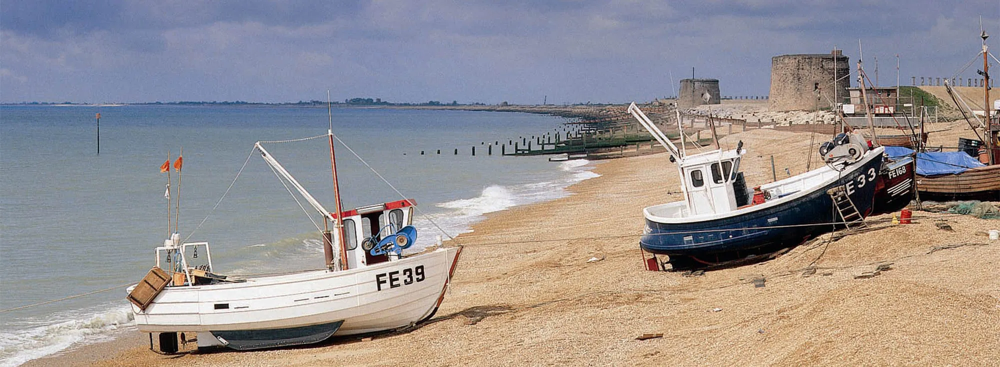 The beach at Dymchurch, a popular holiday destination in Kent, with boats parked up on the shingle.