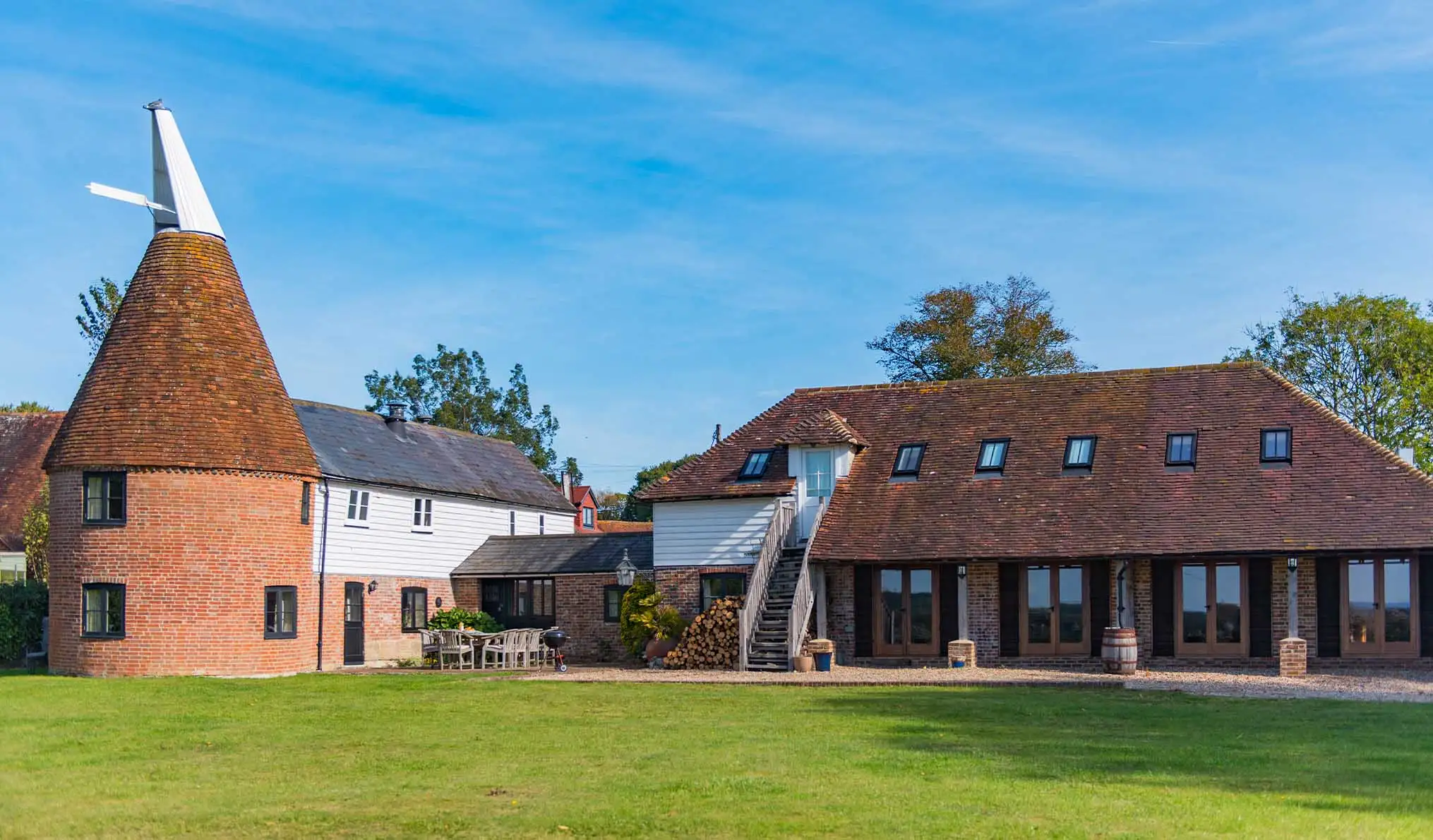 A sunny photo of The Oast in Newenden, with blue skies and cut grass