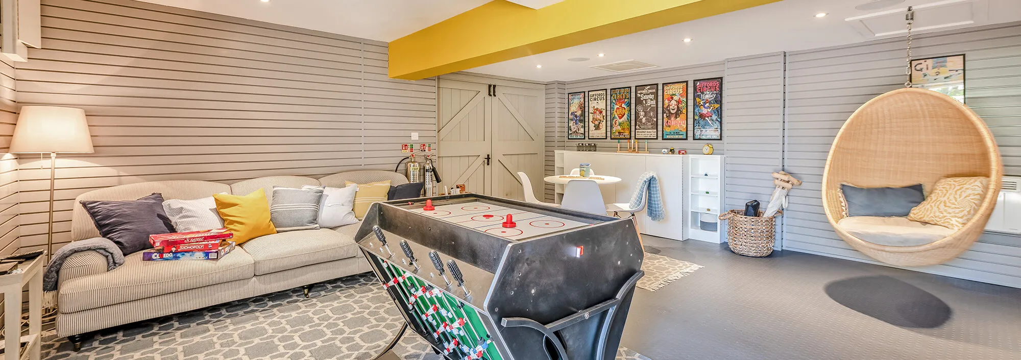 The games room at Bedgebury Oast, fully stocked with board games, jigsaws, and muti-use games table with air hockey and table football. There's colourful comic book posters on the walls creating a fun and laid back atmosphere.