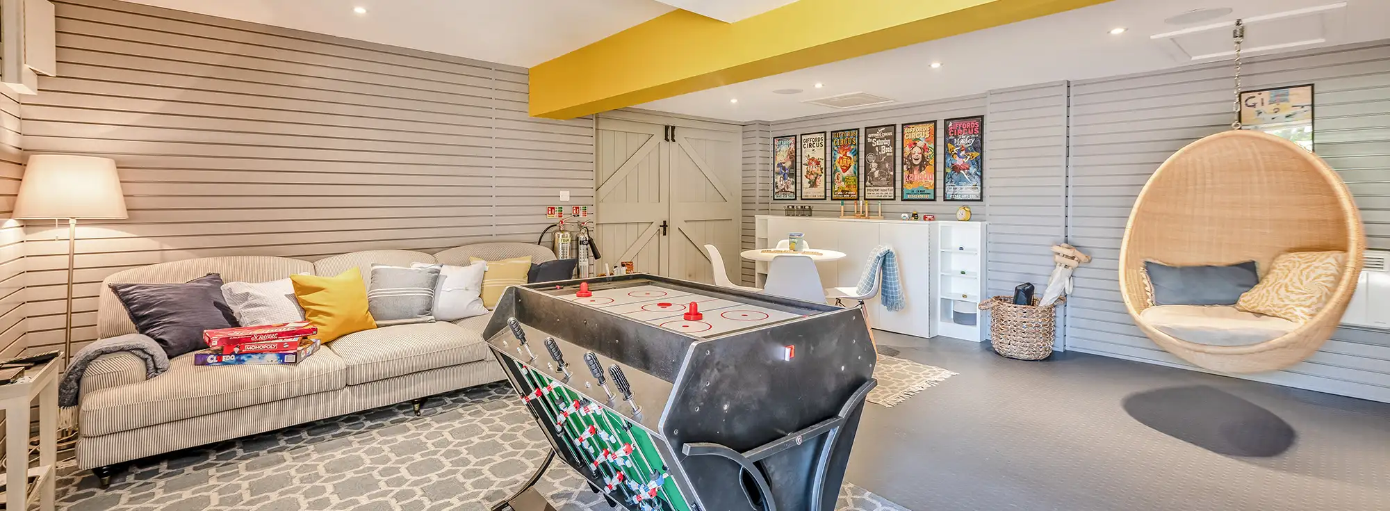 The games room at Bedgebury Oast, fully stocked with board games, jigsaws, and muti-use games table with air hockey and table football. There's colourful comic book posters on the walls creating a fun and laid back atmosphere.