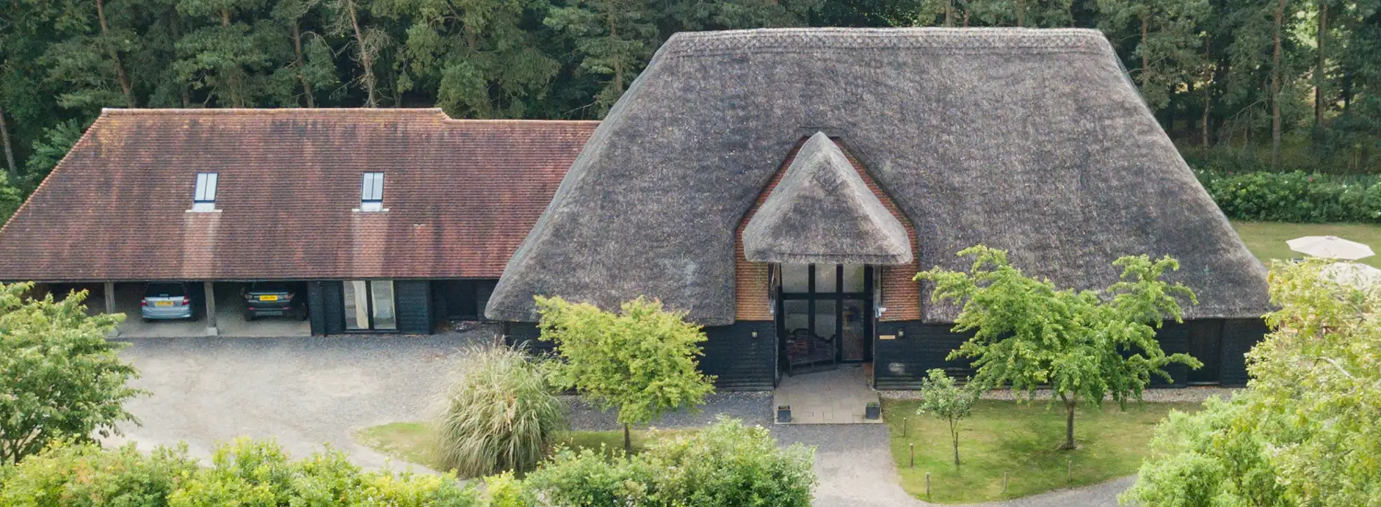 An aerial view of Great Higham Barn, a large holiday home in Doddington, near Faversham. The thatched roof creates a special escape for large groups of friends or family reunions complete with a tennis cout, swimming pool and hot tub, as well as plenty of parking.