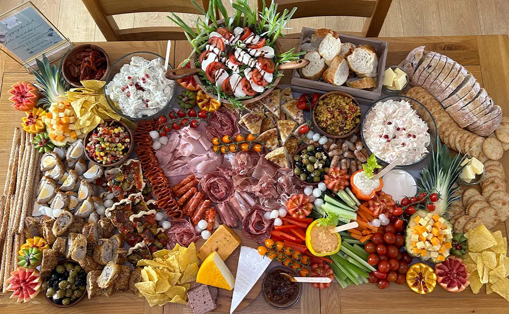A table spread of an array of cold meats, cheeses and snacky food by the Lazy Grazing Company