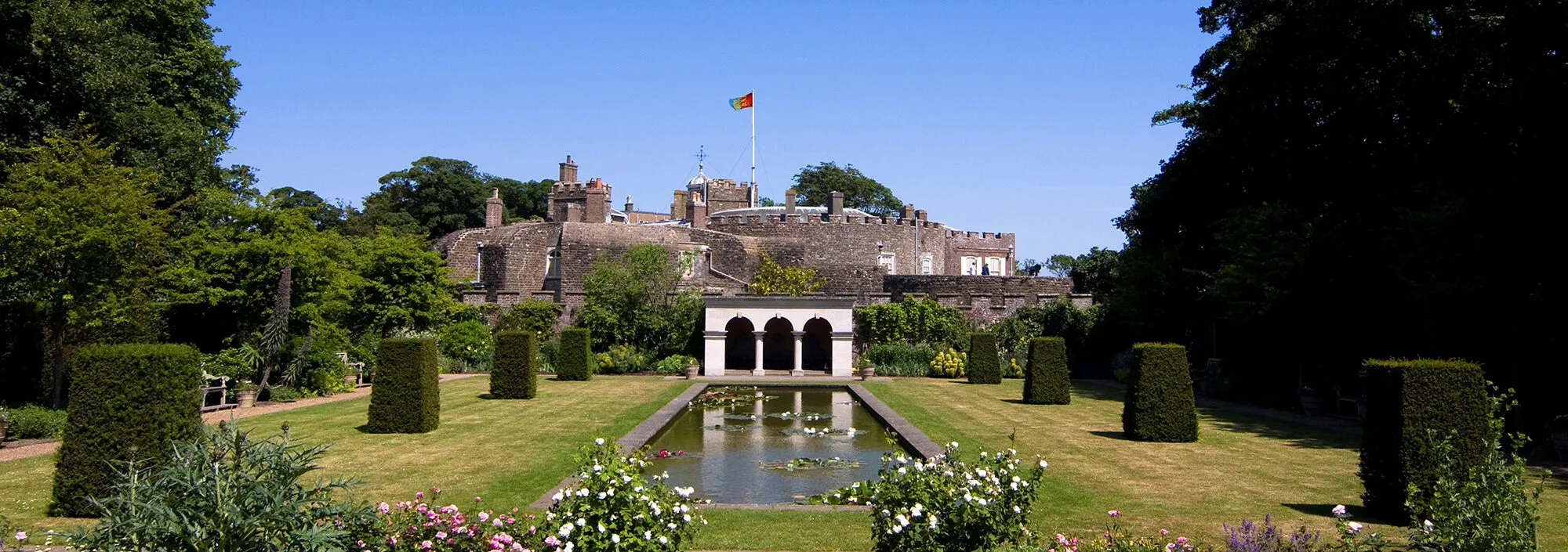 Sunny garden shot with trimmed hedges and Walmer Castle in the background