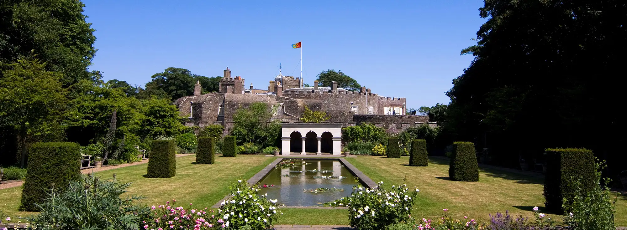 Sunny garden shot with trimmed hedges and Walmer Castle in the background