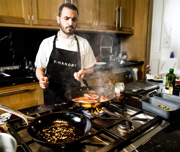 A private Chef from Yhangry cooking in a holiday home with food in a frying pan.