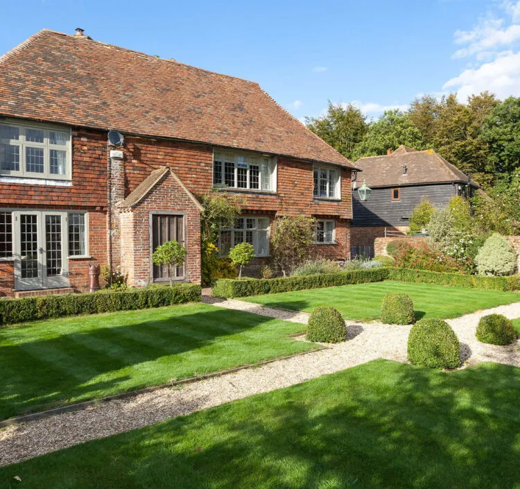 A sunny shot of Dormestone House with neat hedges and freshly mowed grass