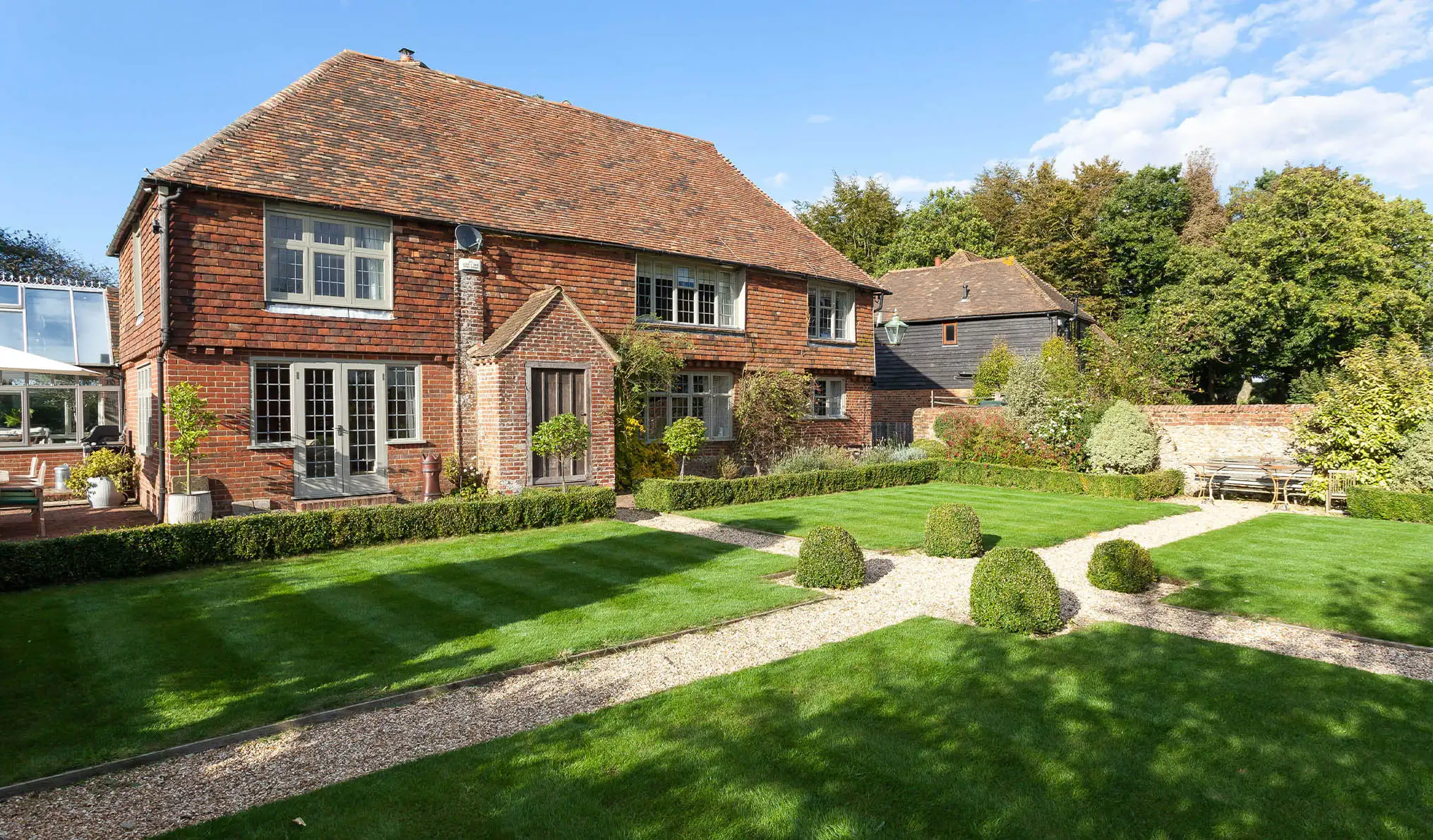 A sunny shot of Dormestone House with neat hedges and freshly mowed grass