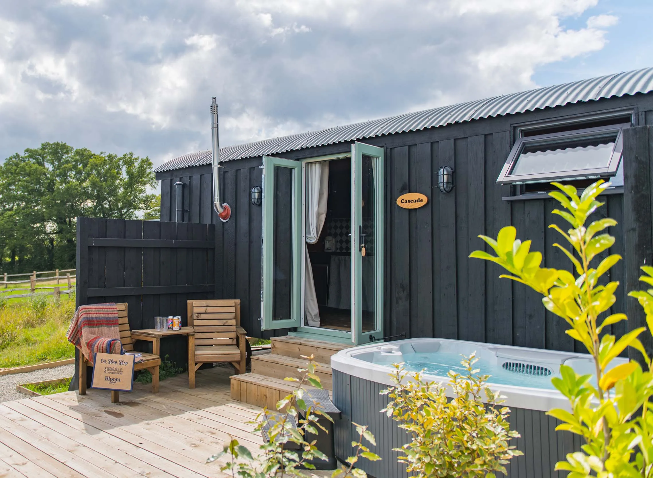 Photo of a cabin with a hot tub and chairs positioned outside on the decking of Cascade, a holiday home on Mccann's Brewery in Tenterden.
