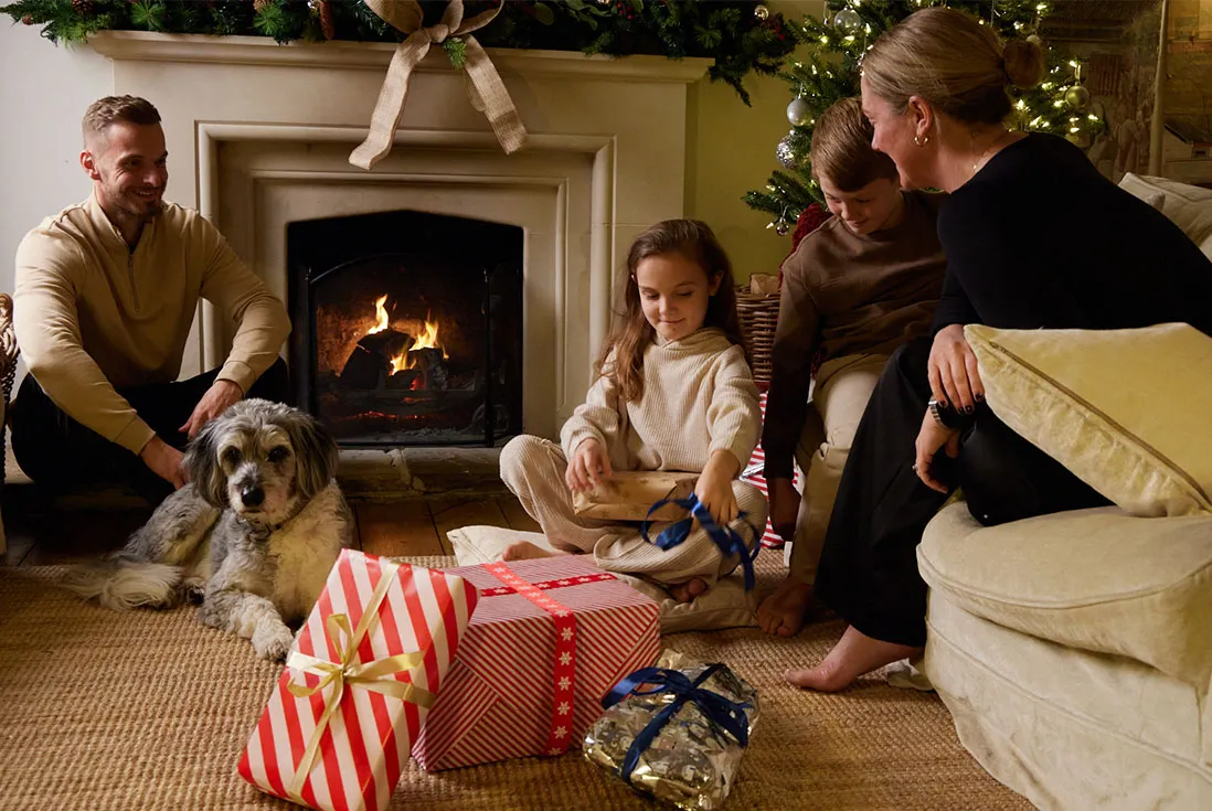 Kids opening presents around the log fire and decorated tree