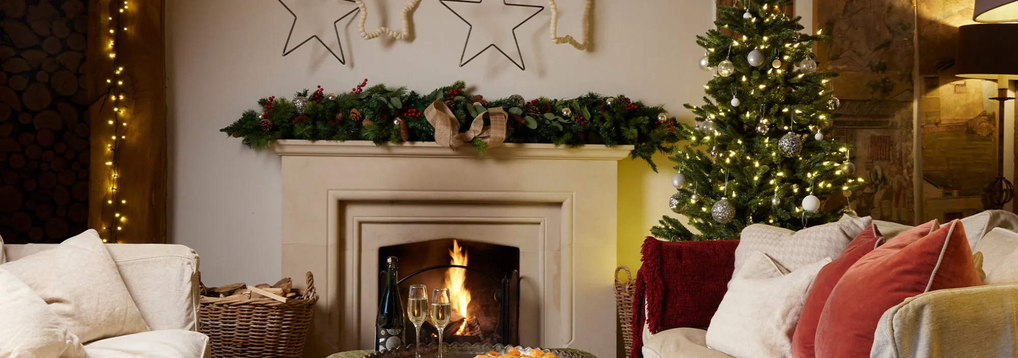 A Christmas cottage with a lit fire and fully decorated Christmas Tree