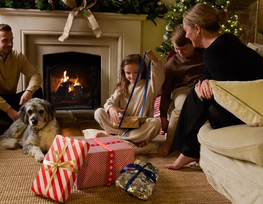 Kids opening presents sat around a fire and decorate christmas tree at a Bloom Stays holiday home