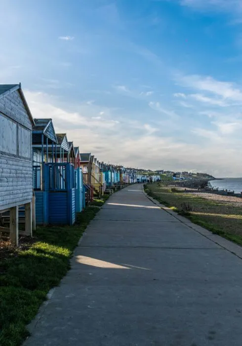 Whitstable beach, showing the town's famous beach huts on the left of the promenade (facing west), and the beach and ocean to the right