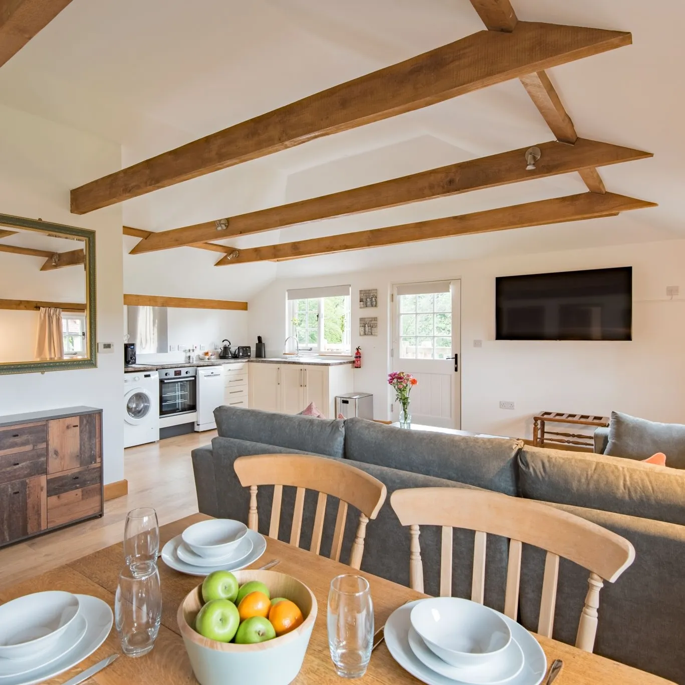 The inside of Motor House Loft with an open plan dining table, living room sofas and kitchen
