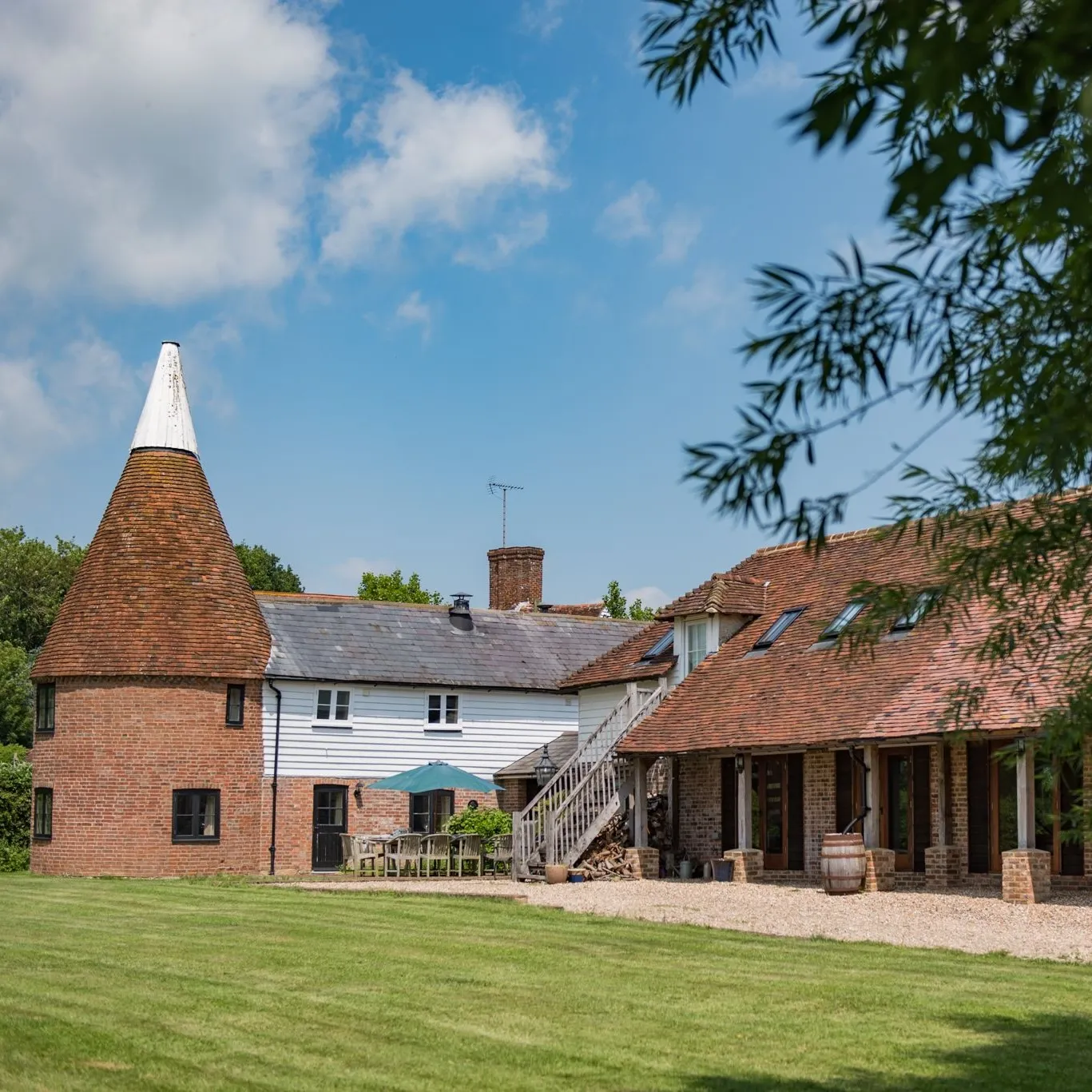 The exteriors of The Oast in Newenden, with a table and chairs for outdoor dining.