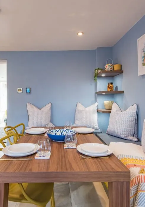 The bright and cosy dining space at Wheelwrights Cottage in Staplecross Nr Rye. The table is laid with plates, glasses and cutlery.