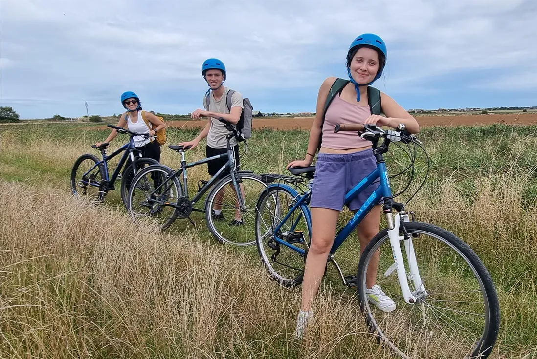 A group of friends on a Col's Kent Bike Tour riding through a field