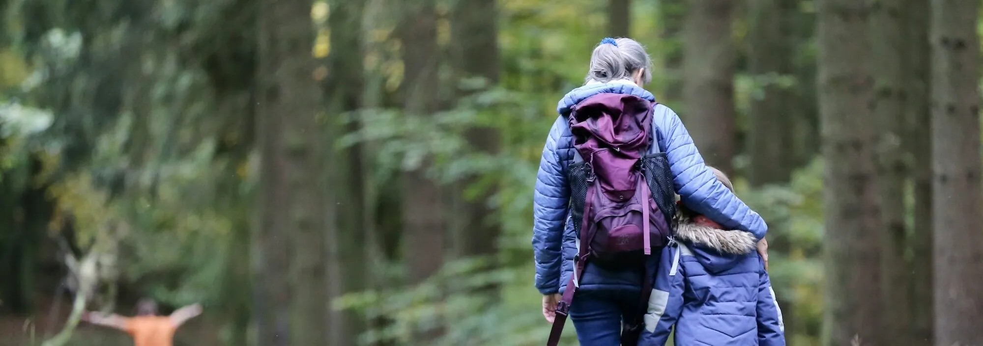A woman walking with her young ones through a forest | Walking trails in Kent – Bloom Stays