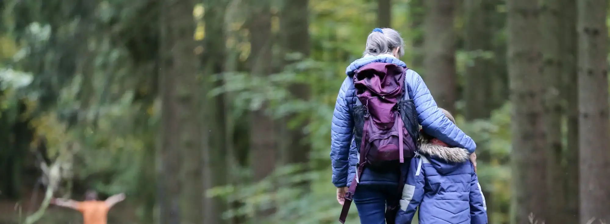 A woman walking with her young ones through a forest | Walking trails in Kent – Bloom Stays