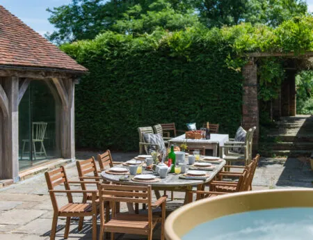 A sunny outdoor table set for breakfast and a hot tub in the corner